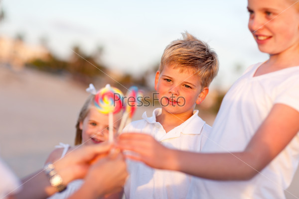 Cute Brother and Sisters Picking out Lollipop from Their Mom at the Beach.