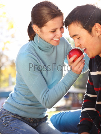 Happy young couple in love with apple outdoors
