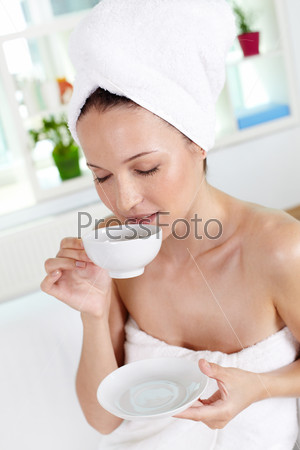 Vertical shot of young woman enjoying tea in spa salon