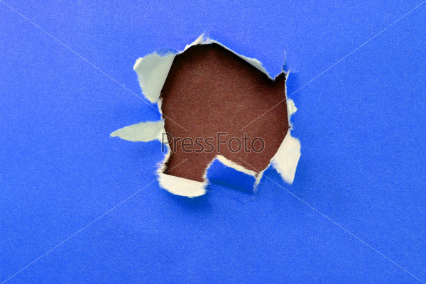 hole in the blue paper with ragged edges and brown texture