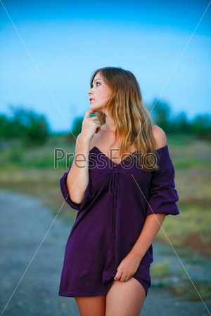 young woman knitted dress of purple on blue background with natural breasts and shoulders bare feet