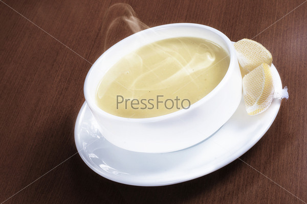 Hot delicious lentil soup with smoke and lemons on wooden table