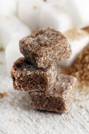 Little heap of white and brown sugar cubes on a white wooden surface