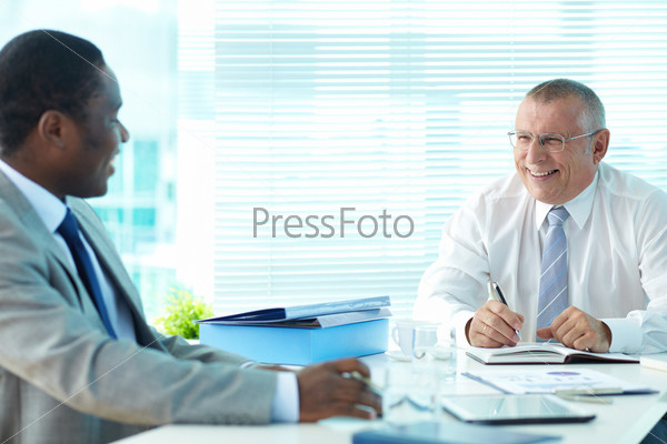 Portrait of senior boss and his employee laughing at meeting