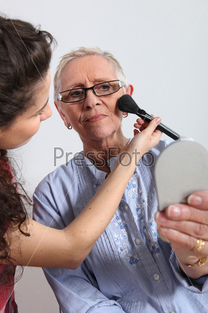 Young woman making up a senior woman