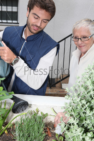 young man and older woman watering plants