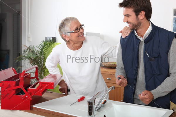 Plumber repairing sink for old lady