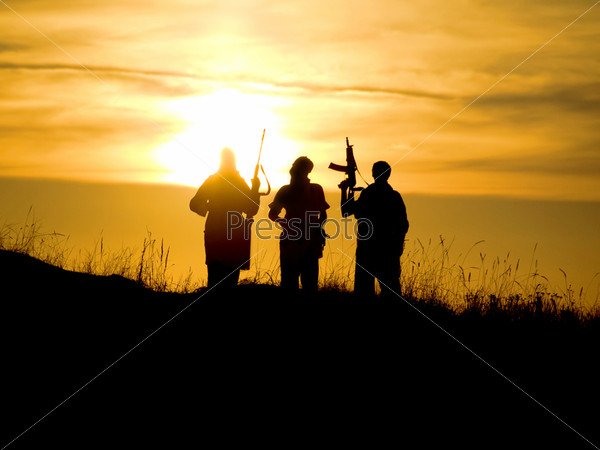 Silhouettes of several soldiers with rifles against a sunset