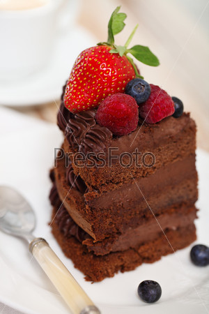 Piece of chocolate cake with icing and fresh berry