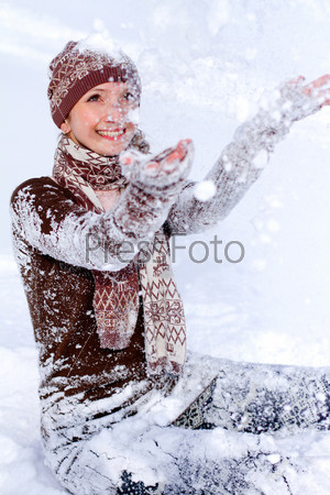 Laughing young woman tossing snow