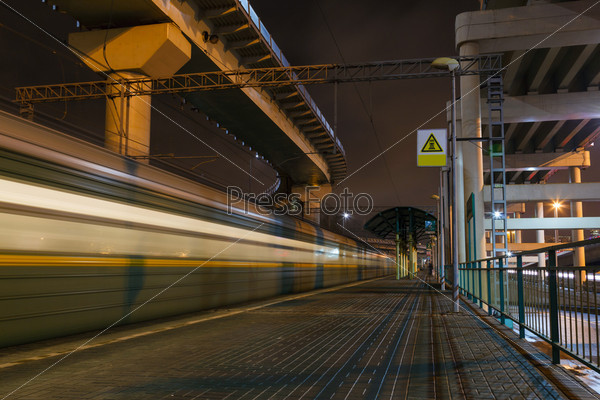 Night train station in the city and a passing train