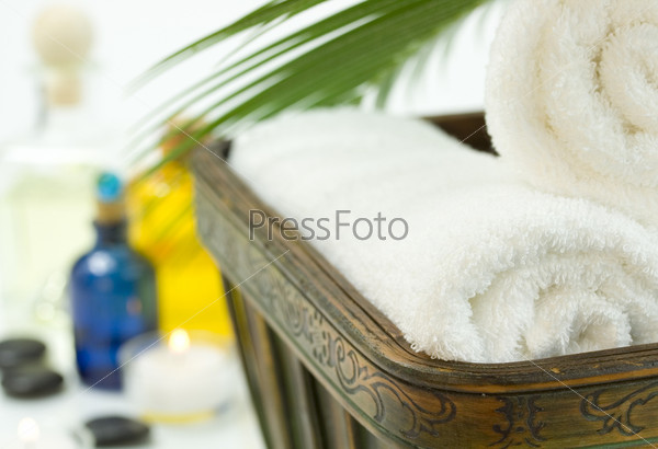 Spa Bath Towels, essential oil, candles and palm leaf on a white background