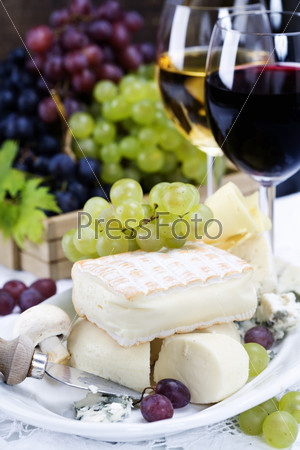Grape and cheese with a bottle and glasses of red and white wine