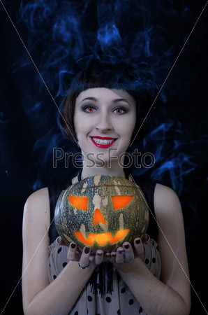 Halloween witch with a pumpkin. Blue smoke background