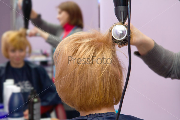 Hairdresser drying woman hair in salon