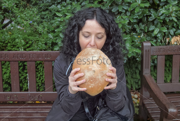 Portrait of hungry pretty young brunette eating huge bread