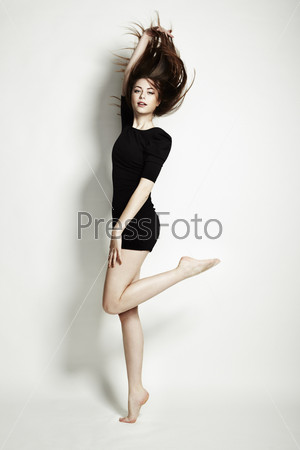 Young charming female in black dress jumping over white background. Fashion photo