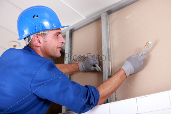 Technician in action, installing wires in a wall