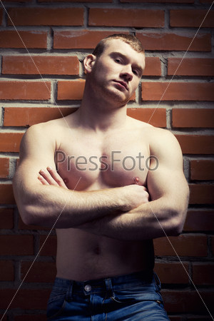 Young athlete bodybuilder man near brick wall