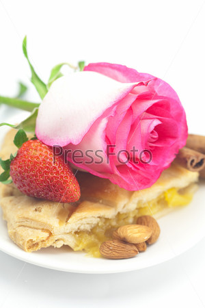 piece of apple pie, cinnamon, pink rose, almonds and strawberries isolated on white