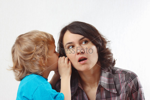 A little boy whispers to his mother something into her ear