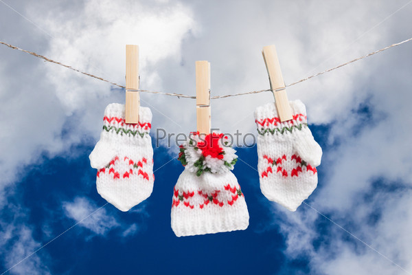 hat and pair of gloves drying in the open air hanging on clothes line affixed with wooden pegs