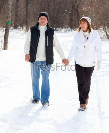 Happy seniors couple in winter park. Elderly mature people