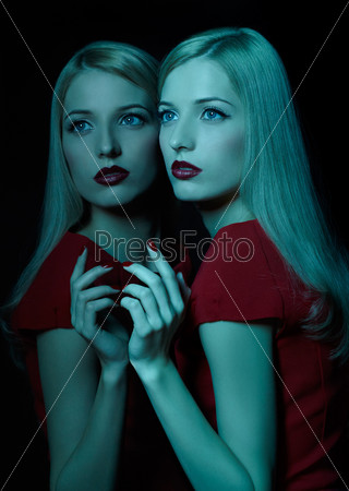 portrait of beautiful young blonde woman in teal lighting posing at mirror