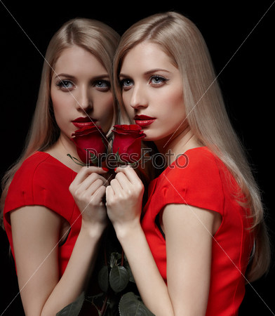 portrait of young beautiful blonde woman in red dress with red rose posing at mirror face to face with her reflection