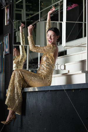 Young woman in gold dress have fun on bar table