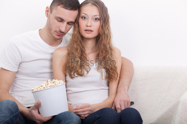 young couple sitting on the sofa with popcorn, guy sleeping, girl obsessed with film