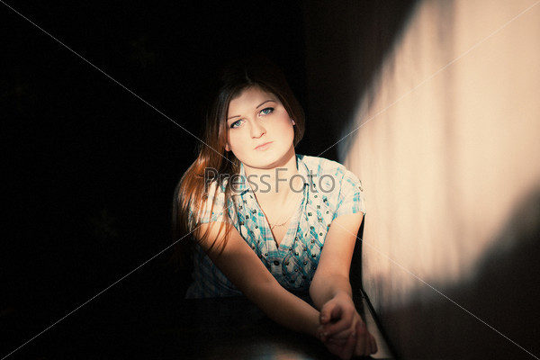 Young woman suffering from a severe depression in a line of light