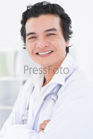 Vertical portrait of a happy handsome physician being friendly and self-confident