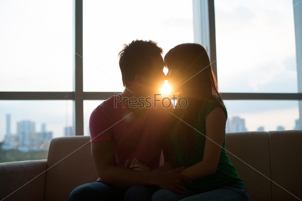 Young couple kissing on sofa with sunset in the background