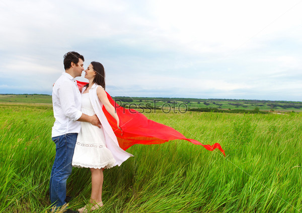 Young happy couple in love with red fabric in summer day