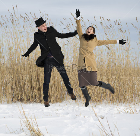 Happy man and woman jump on lake beach