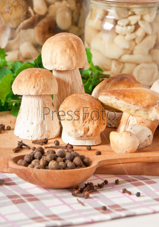 boletus on wooden cutting board, spices, oil and spoon