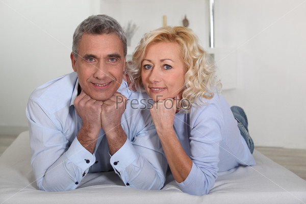 Man and woman lying with their heads propped up on their hands