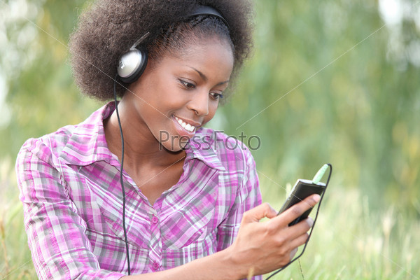 Woman stood outdoors holding portable digital music player