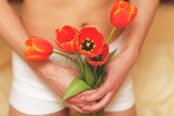 Romantic young man with flowers. Focus on flowers.