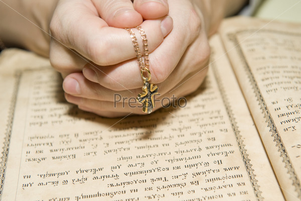 Женские руки на православной Библии во время чтения молитвы