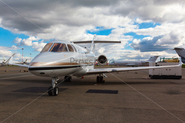 White reactive private jet, the front landing gear and a\
ladder on blue sky and clouds