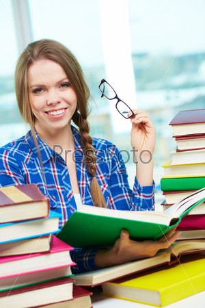 Portrait of diligent student looking at camera with open book in hands