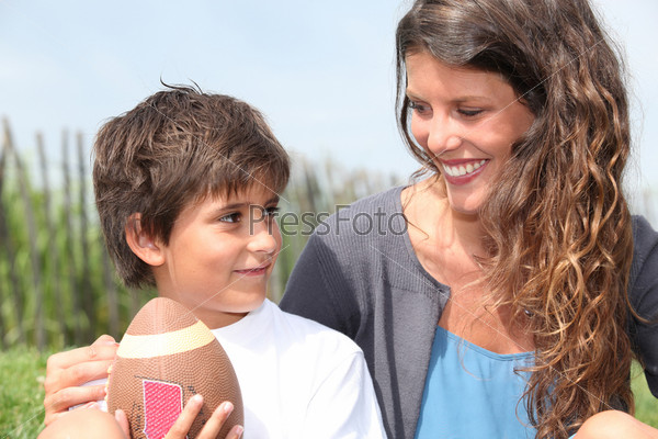 little boy with American football sat with mother