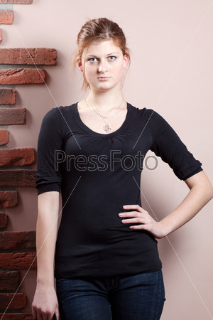Earnest woman in black shirt standing against a wall