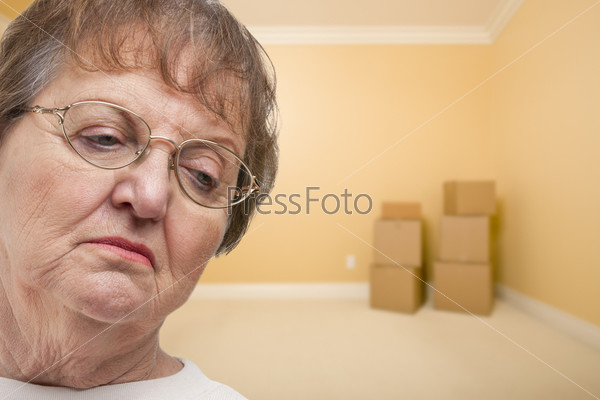 Грустная пожилая женщина в пустой комнате с коробками