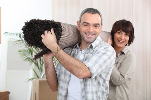 Couple carrying rug, stock photo