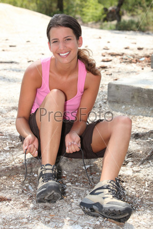 Woman sat outdoors tying shoelaces
