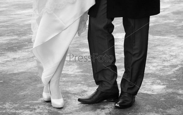 Close-up wedding shoes of bride and groom in outdoor. Black and white.