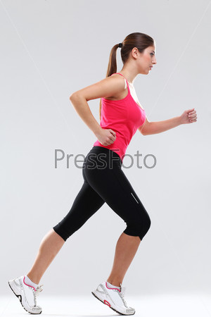 Young beautiful woman in fitness wear runs isolated over background
